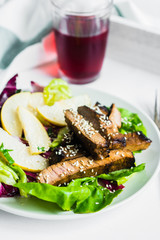 Sliced meat steak with green salad and pears