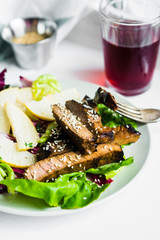 Sliced meat steak with green salad and pears