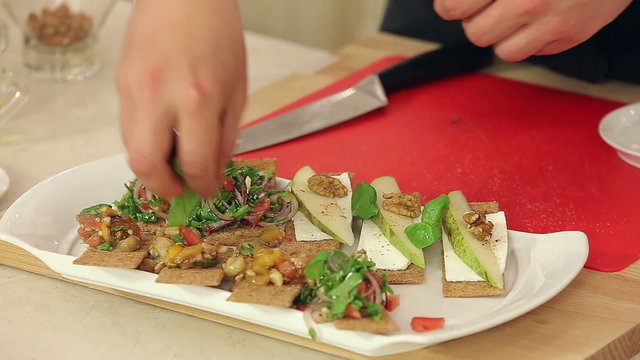 Chef is Making Bruschettas with Vegetable Mix, Pears and Nuts