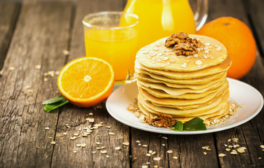 delicious pancakes on wooden table with orange and orange juice