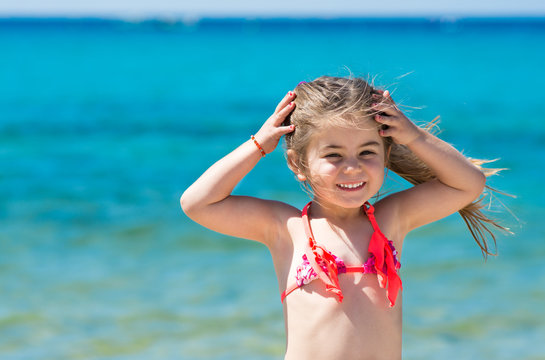 Happy smiling little girl on beach vacation, blu sea background