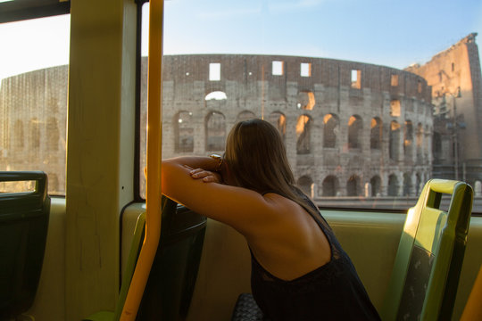 Frau sieht aus dem Fenster einer Straßebahn auf das Kolosseum in Rom