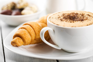 Hot cappuccino and pastries on white wooden boards