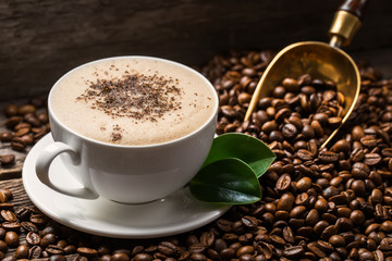 Close-up of coffee cup with roasted coffee beans on wooden background.