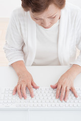 Fototapeta premium パソコンのキーボードを使っている高齢者の女性