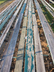 The old wooden bleachers offer peeling paint on the seats to the spectators at a football field.