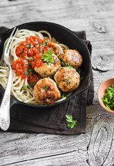 chicken meatballs and spaghetti in a pan on a light wooden background