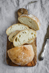 homemade rustic bread with olive cutting Board on gray fabric surface