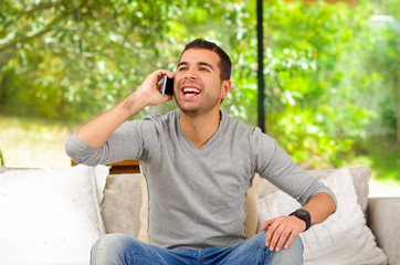 Hispanic man wearing denim jeans with grey sweater sitting in