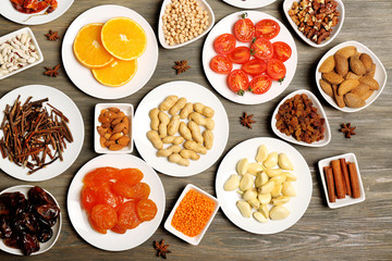 Different products on saucers on wooden table, top view