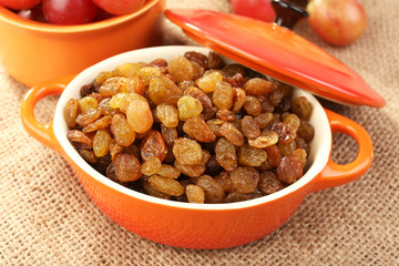 Raisins in bowl with grapes on table close up