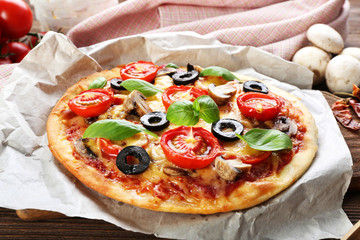 Tasty pizza with vegetables and basil on table close up