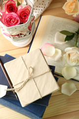 Fresh roses with old book, key and letters on wooden table background. Vintage concept