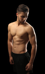 Fototapeta na wymiar Muscle young man on dark background