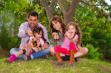 Fototapeta premium Family portrait of father, mother and two daughters sitting