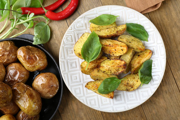 Baked potatoes with basil leaves in white plate on wooden table, top view