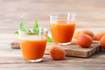 Glasses of apricots juice on wooden background