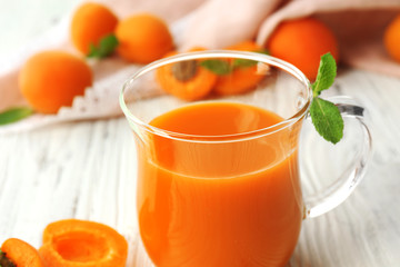 Cup of apricot juice and fresh fruits on table close up