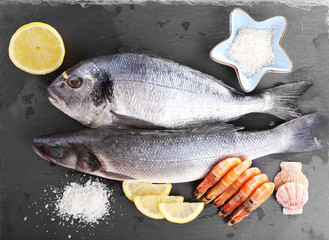 Fresh fishes and shrimps with spices  on gray background