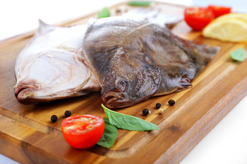 Fresh fishes with spices on cutting board close up