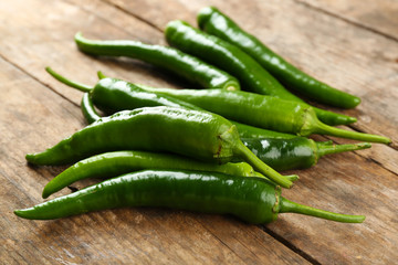Green hot peppers on wooden table close up