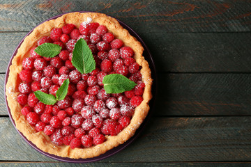 Tart with fresh raspberries, on wooden background