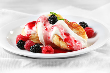 Fritters of cottage cheese with berries in plate, closeup