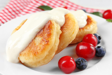 Fritters of cottage cheese with berries in plate, closeup