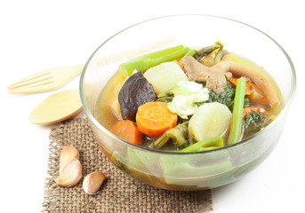 Fresh hot vegetable soup and spoon on wood