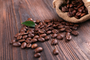 Coffee beans with leaf on wooden table close up