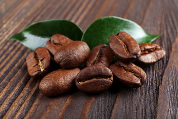 Coffee beans with leaves on wooden background