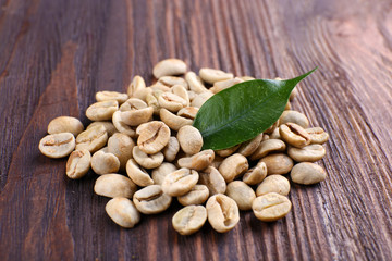 Green coffee beans with leaf on wooden background