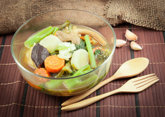 Fresh hot vegetable soup and spoon on wood