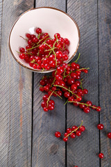 Fresh red currants in bowl on wooden table close up