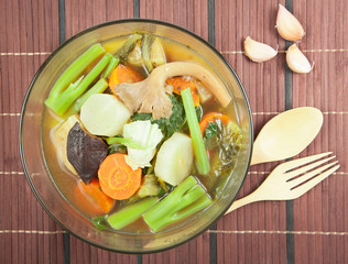 Fresh hot vegetable soup and spoon on wood