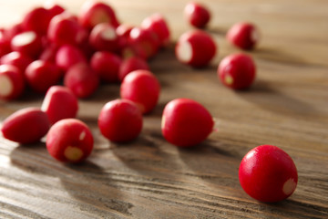 Heap of fresh radishes on wooden table close up background