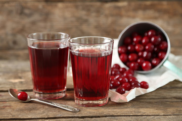 Two glasses with cherry juice on table, on wooden background