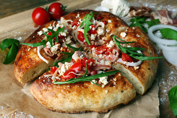 Greek homemade pizza with ham,onion, roasted tomato, creamy feta on wooden table background