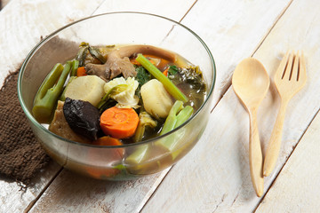 Fresh hot vegetable soup and spoon on wood