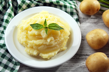 Mashed potatoes in plate on wooden table with checkered napkin, closeup