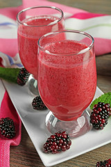 Glasses of blackberry smoothie on wooden table, closeup