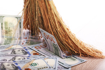 Dollars and broom on wooden floor, closeup