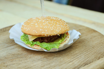 Tasty hamburger on wooden table close up