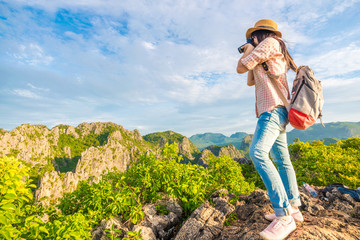 Hiker woman with camera enjoy the view at sunrise mountain peak