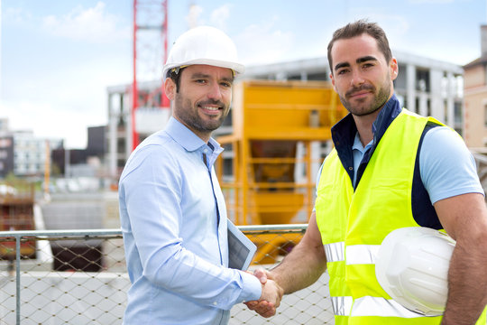 architect and worker handshaking on construction site