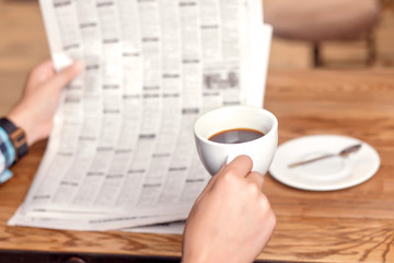 Man reading newspaper and drinking coffee