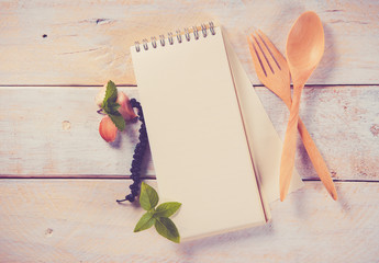 Cookery book and wooden spoon on wooden background