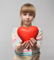 little girl holding a red heart in hands