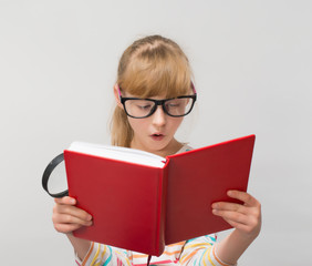 Little girl with a book and a magnifying glass