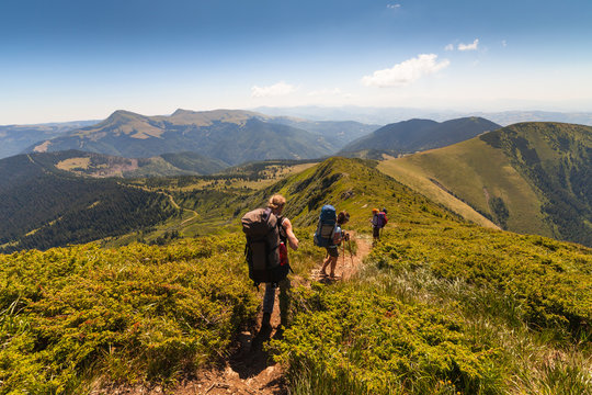 A group of people with backpacks walking along the road.
